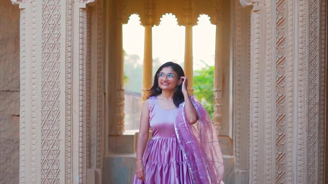 Portrait of beautiful Indian young woman in Hindu temple at Bhuj, Gujarat, India. Indian architecture and Hindu religion concept. Carving on stone pillars and window in background. Travel India.