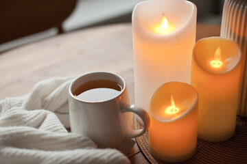 Cozy winter home interior with warm candlelight, wool sweater, hot tea and LED decor creating a calm hygge atmosphere