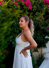 portrait of a beautiful young woman in a white dress smiling at camera in the garden