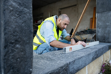 Construction worker leveling a stone surface outdoors