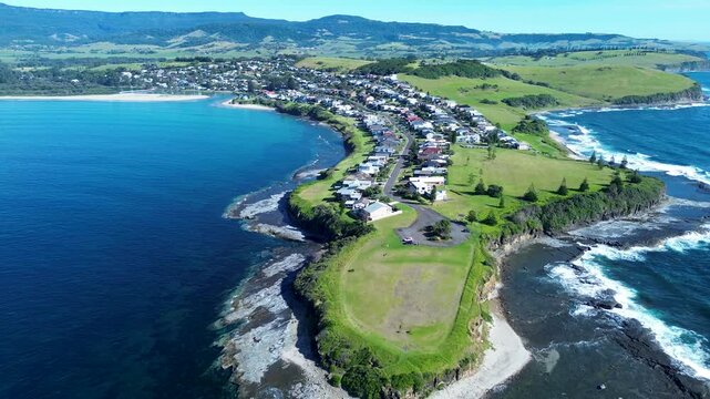 Drone aerial landscape of Gerroa town suburbs with rural housing along streets and a beautiful ocean coastline with waves and headland on South Coast Gerringong Illawarra NSW Australia travel tourism