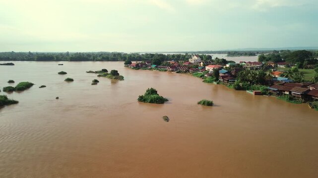 Aerial of Don Det island showing river channels, boats, and green banks under warm sky, establishing pan