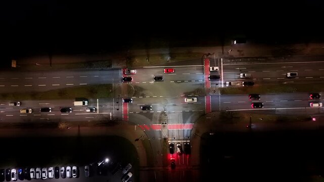 Traffic scene on junction of highway in American town. Driving cars on lighting street at night. Aerial top down shot.