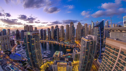 Modern skyscrapers and water channel with boats of Dubai Marina at sunset and day to night...