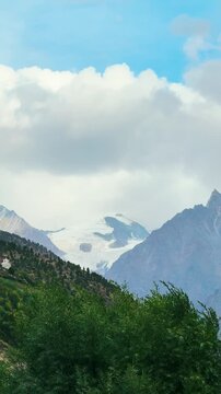 4K Vertical shot of clouds above the Lady Of Keylong mountain peak as seen from Keylong in Lahaul, Himachal Pradesh, India. Mountain peak covered with glacier. Nature landscape. Summer Himalayas.
