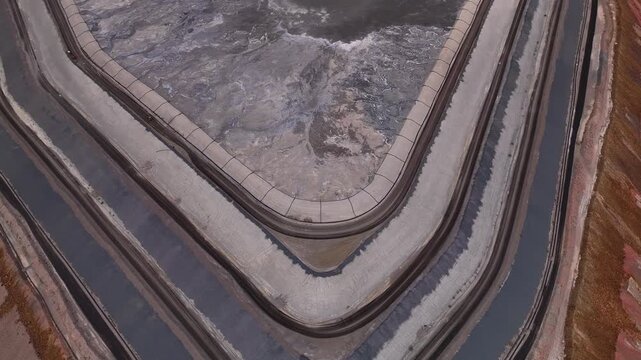 Aerial view of a reservoir filled with swirling grey water, embankments of grey concrete, and the surrounding red earth, Tucson, Arizona, United States.