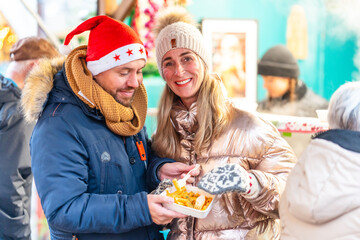Happy couple dining at a Bavarian Christmas market in Germany enjoying festive flavors and bright winter lights