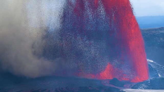 Aerial view of the Kilauea volcano erupting with fiery red lava cascading down its side amidst a cloud of smoke and ash, Kilauea, Hawaii, United States.