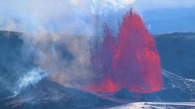 Aerial view of a volcano erupting, spewing bright red lava into the air with white smoke billowing around, a powerful display of nature, Kilauea, Hawaii, United States.