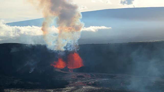 Aerial view of the fiery Kilauea volcano erupting, contrasting vividly against the dark volcanic landscape and cloudy skies, Kilauea, Hawaii, United States.