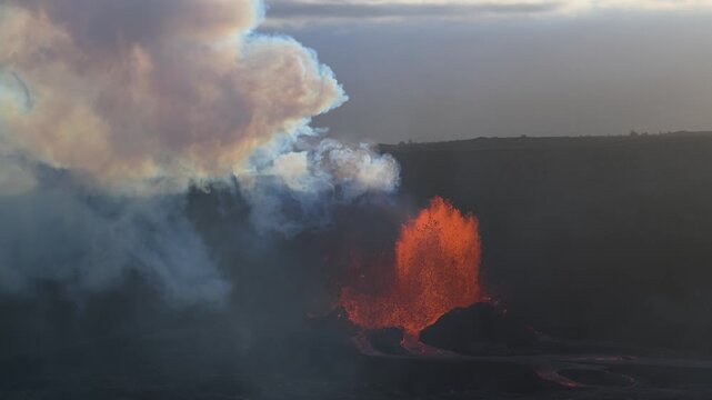 Aerial view of the Kilauea volcano erupting, with vibrant orange lava contrasting against the dark landscape and smoke plumes, Kilauea, Hawaii, United States.