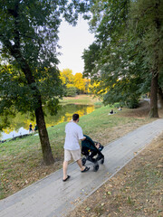 Man walking with a stroller in a park during sunset.