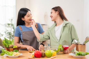 Friends cooking in a kitchen while smiling and enjoying preparing healthy food together