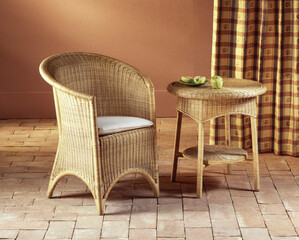 Still life of a wicker armchair and coffee table, on a stone floor