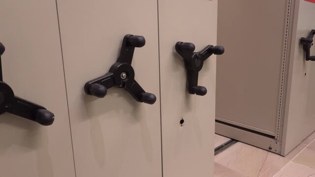 New York, NY USA Rotating manual levers in large filing cabinet used to move shelves.  