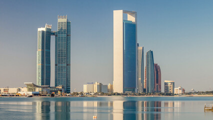 Abu Dhabi city skyline with skyscrapers after sunrise with water reflection timelapse