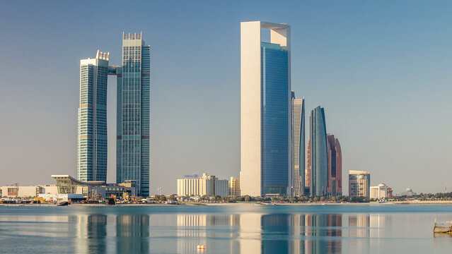 Abu Dhabi city skyline with skyscrapers after sunrise with water reflection timelapse - Powered by Adobe