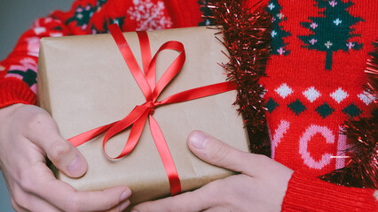 Girl or a woman in a Christmas sweater with a gift box. Christmas present.