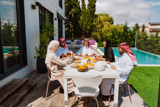 Arab family enjoying outdoor meal in modern backyard - Powered by Adobe