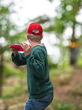 Young person preparing disc golf throw in lush green forest setting.