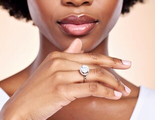 Close-up of a womans hand with an engagement ring, resting on her chin, showcasing her beautiful lips and skin.