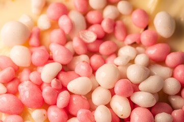 Pink and white anise seeds, pelleted in sugar, close up. On a rusk with butter, often served at the first baby visit.
