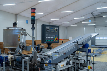 Automatic industrial machine with control panel and conveyor in factory hall