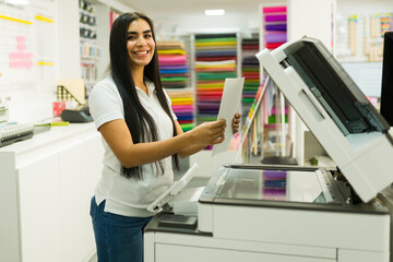 Hispanic female worker making photocopies at copy and print shop