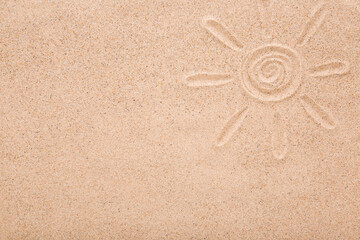 Drawn sun shape with rays on dry light brown sea sand background. Closeup. Summer concept. Empty place for text. Top down view.