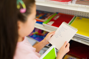 Closeup of a girl checking back to school supplies list in store