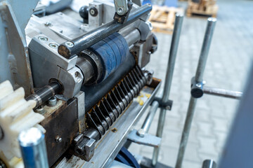 Naklejka premium Close-up of industrial cutting and feeding mechanism with rollers and blades