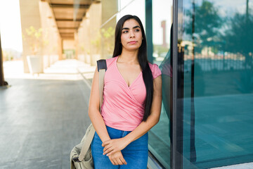 Female student woman standing thoughtfully on university campus, contemplating education and future during college break
