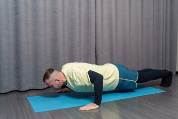 A young man is doing push-ups. Strengthening body muscles with physical exercises. Home fitness workout.