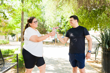 Active couple toasting with healthy smoothies after a workout, enjoying a healthy lifestyle outdoors in a park