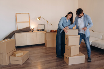 Using scotch as glue. Couple packing cardboard boxes while preparing to move into a new home