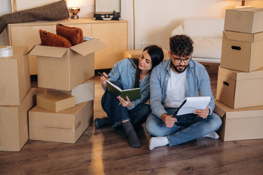Notepad is in hands. Couple reviewing documents and planning their new home after moving