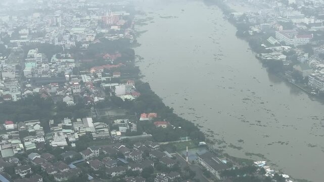 View from aircraft window passing over Song Vam Thuat River and suburbs in Ho Chi Minh City on a stormy morning 