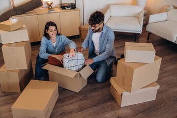 Lovely couple unpacking cardboard boxes together in a new apartment after moving