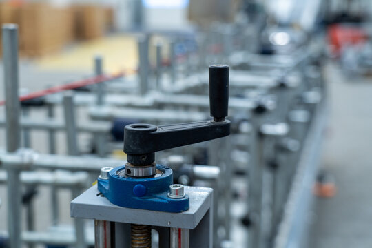Hand crank adjustment handle with blurred industrial machine background