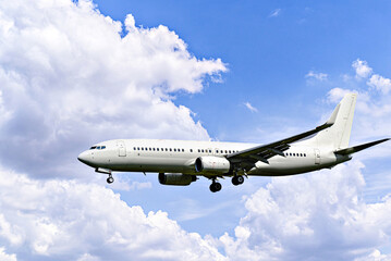 Passenger plane landing at the airport, under a blue sky with white clouds	