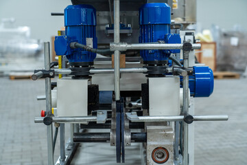 Front view of industrial processing machine with blue electric motors and metal rollers