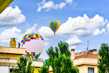 Colorful hot air balloon flying over blue sky with white clouds