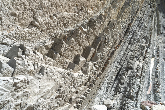 Layered rocks, flysch texture background. Sedimentary rock, striations stone pattern