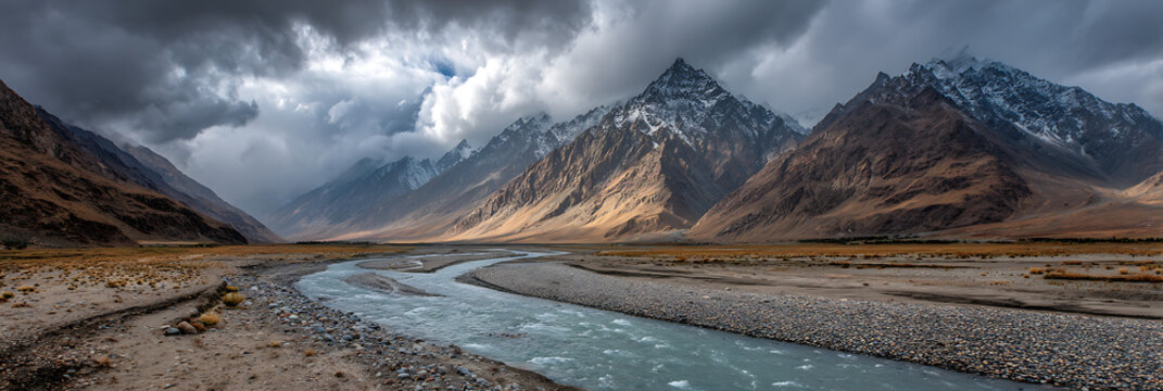 Panoramic landscape of river flowing through mountains under dramatic cloudy sky