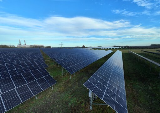 Aerial view of solar panels gleaming under the vast sky, contrasting with the distant industrial structures along Centenary Way, Spalding, England, United Kingdom.