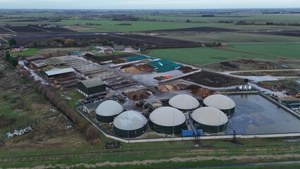 Aerial view of a biogas plant with its rounded digesters contrasting against the flat landscape, Wisbech, England, United Kingdom.