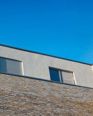 Modern building design with stone facade and clear blue sky in a residential area
