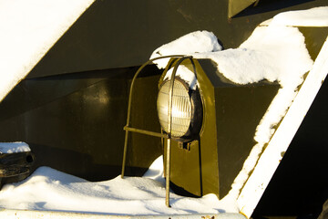 Headlight on a Dark Military or Heavy Vehicle Surrounded by Snow