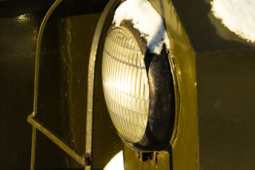 Headlight on a Dark Military or Heavy Vehicle Surrounded by Snow