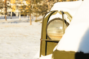 Headlight on a Dark Military or Heavy Vehicle Surrounded by Snow